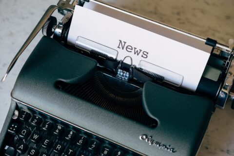 Vanha kirjoituskone, jossa paperilla teksti News.
